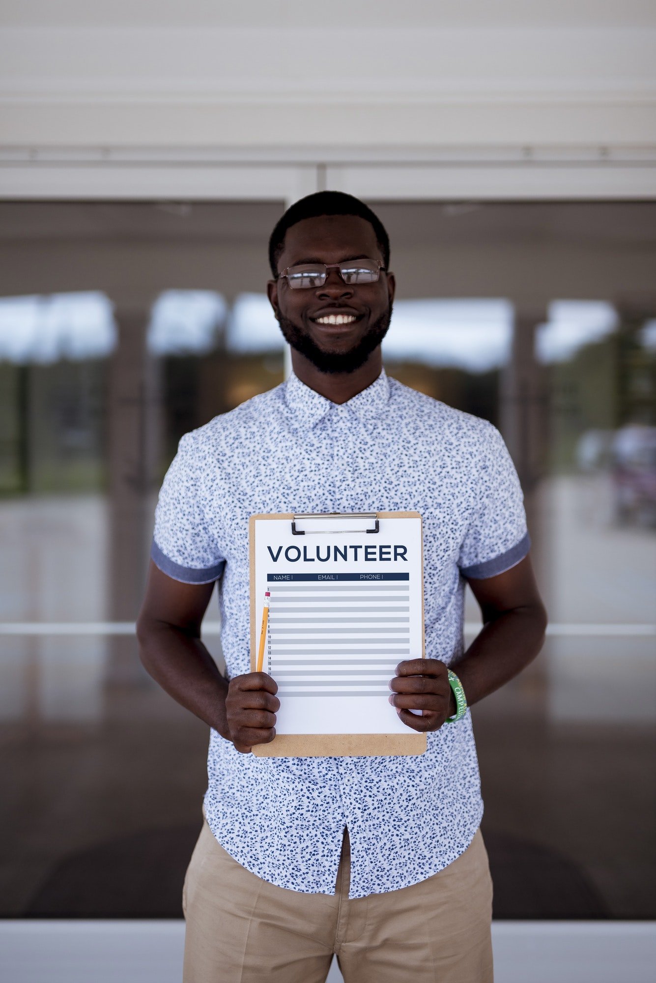 Vertical shot of a male holing a volunteer clipboard while smiling at the camera